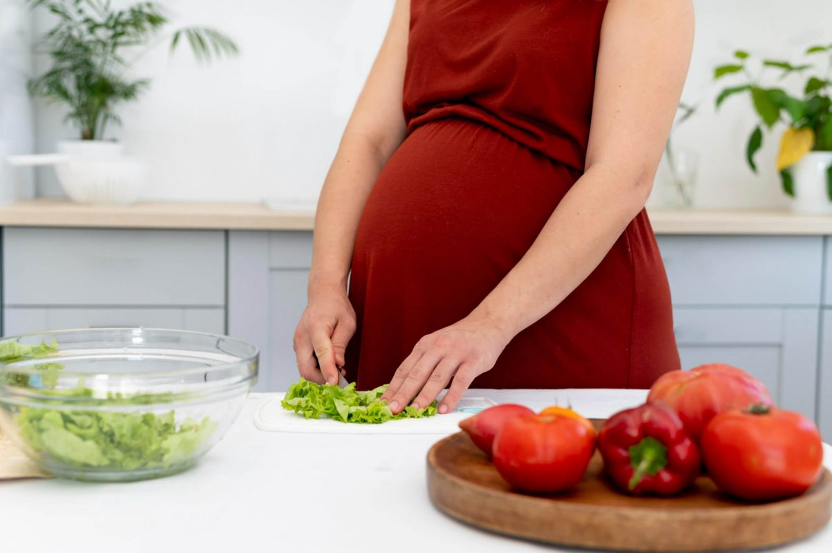 close-up-pregnant-woman-cutting-lettuce
