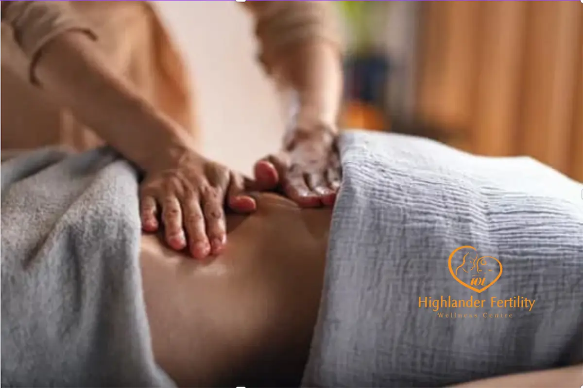 Fertility massage therapist performing a gentle abdominal massage during a fertility wellness treatment session.