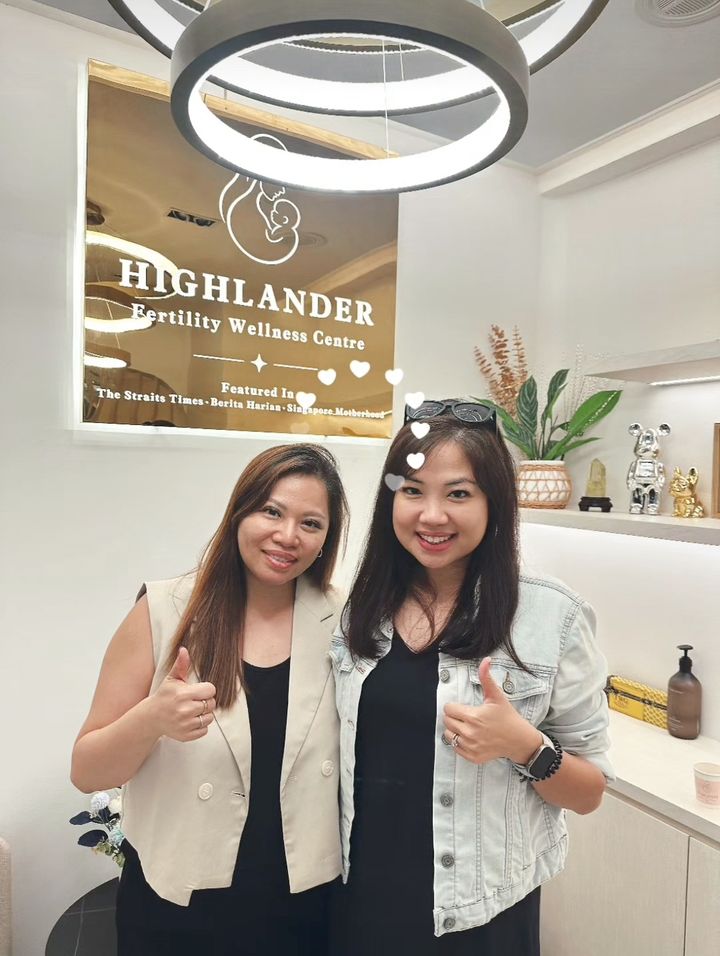 Wendy and a happy client giving thumbs up in front of the Highlander sign